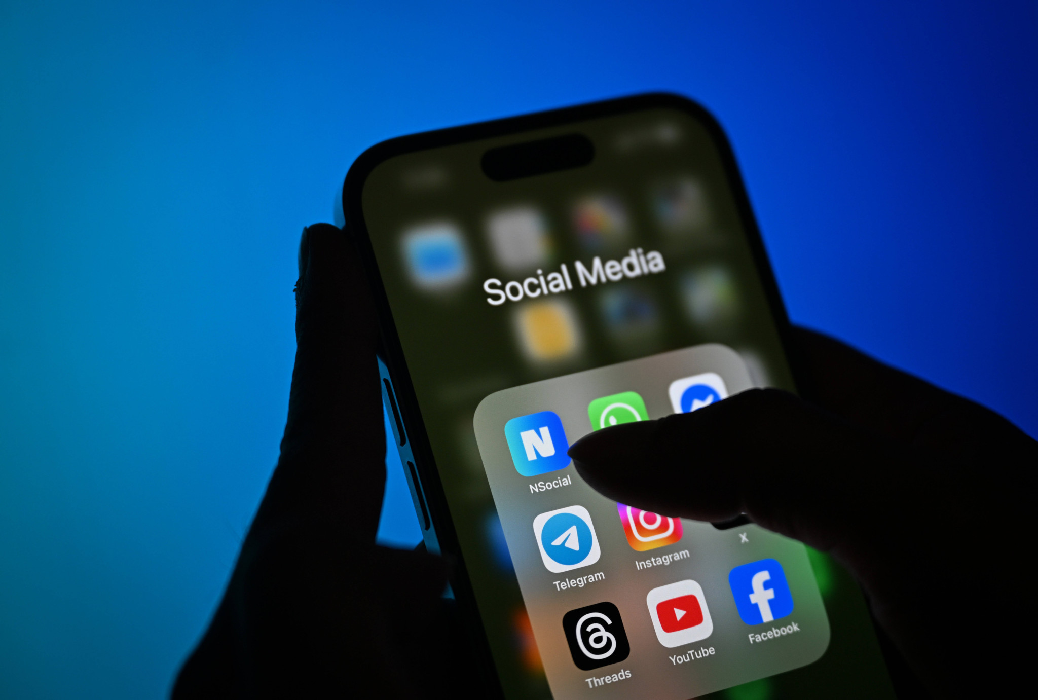 Une main tient un smartphone affichant l’application de médias sociaux Next Sosyal, avec son logo visible, sur un écran d’accueil avec d’autres applications, à Ankara, Turquie.